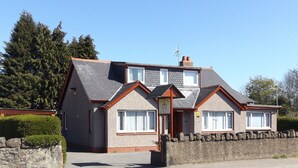 A two-story house with a stone foundation, a sloped roof, and a chimney. - Lyndon Guest House (Inverness)