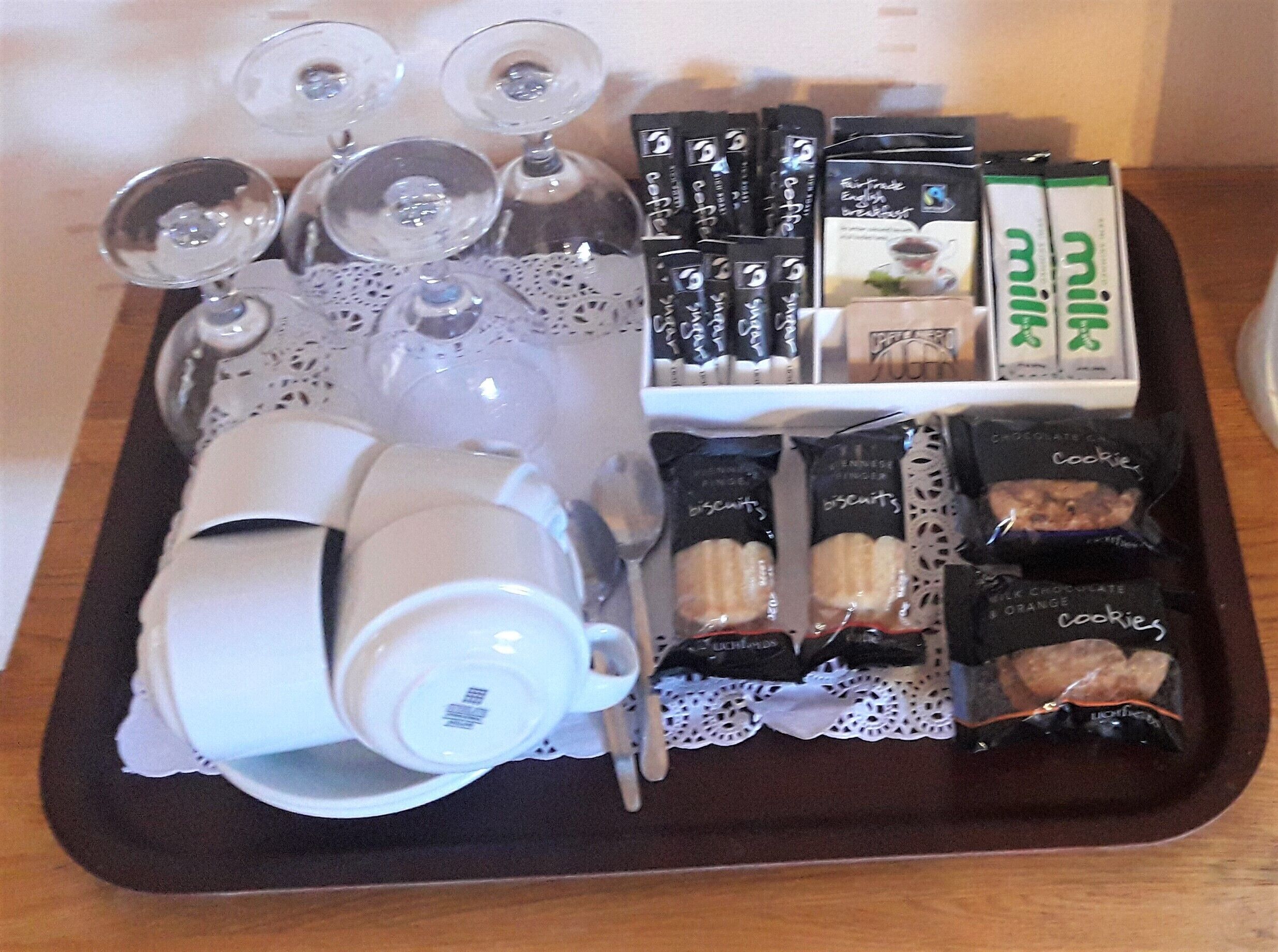 Un plateau avec des sachets de thé, des biscuits et une théière.