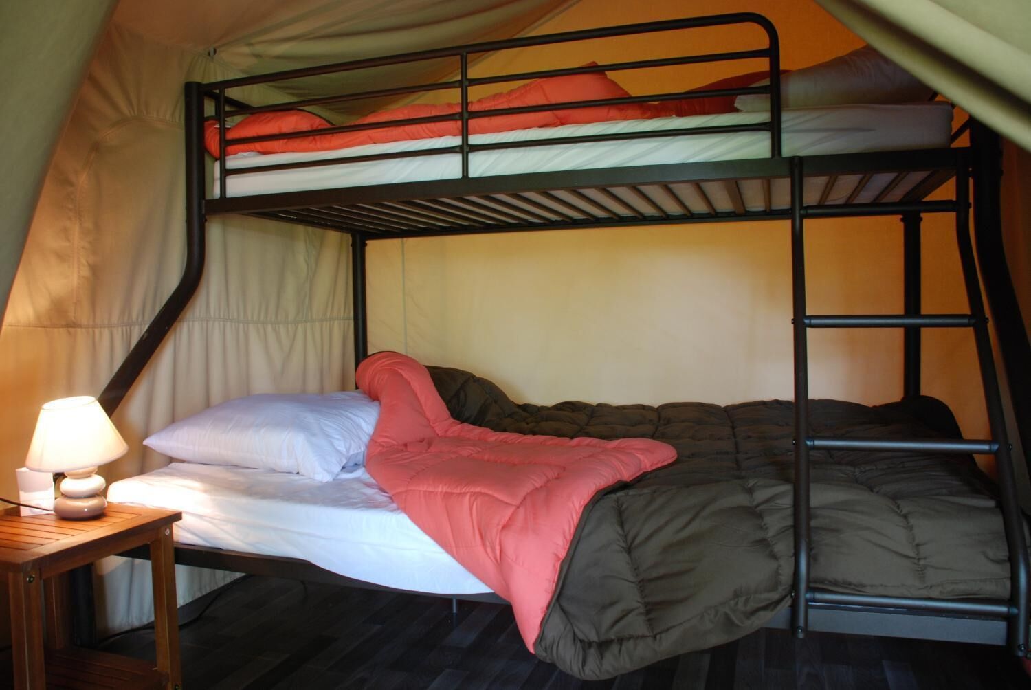 A bunk bed with a wooden table and a lamp.