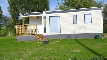 Een gelijkvloerse stacaravan met een veranda, grote ramen en een klein terras.