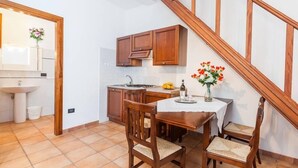 Una cocina con armarios de madera, una mesa de comedor con sillas y una escalera.