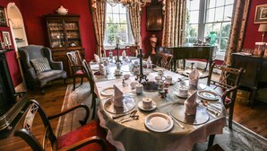 A dining room with a table set for a meal, surrounded by chairs and a chandelier. - Grosvenor Villa (Bath)