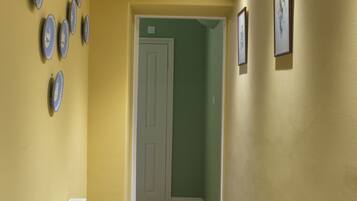 Un couloir avec un tapis bleu, des murs jaunes et un radiateur blanc.