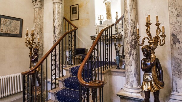 A grand staircase with marble columns and a statue, leading to a higher floor. - Grosvenor Villa (Bath)