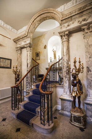 A grand staircase with marble columns and a statue, leading to a higher floor. - Grosvenor Villa (Bath)