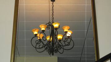 Un candelabro con múltiples luces colgando de una cadena, frente a una pared de azulejos.