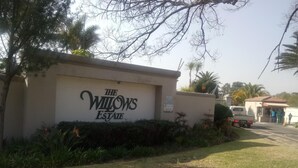 A sign for The Willows Estate with a paved driveway and a parked truck. - Benvenuto Hotel and Conference Centre (Randburg)