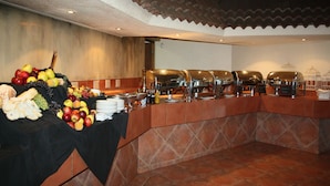 A buffet setup with a variety of fruits and vegetables, multiple serving stations, and a tiled floor. - Benvenuto Hotel and Conference Centre (Randburg)