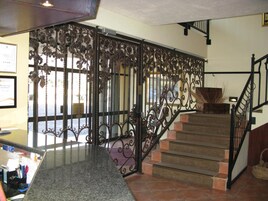 Un escalier orné de rampes en métal ouvragé, offrant une vue sur l’extérieur.