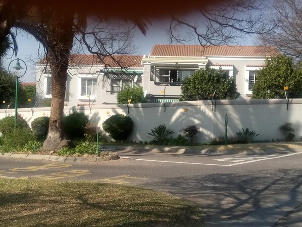A residential area with a white house, a tree, and a clear sky.