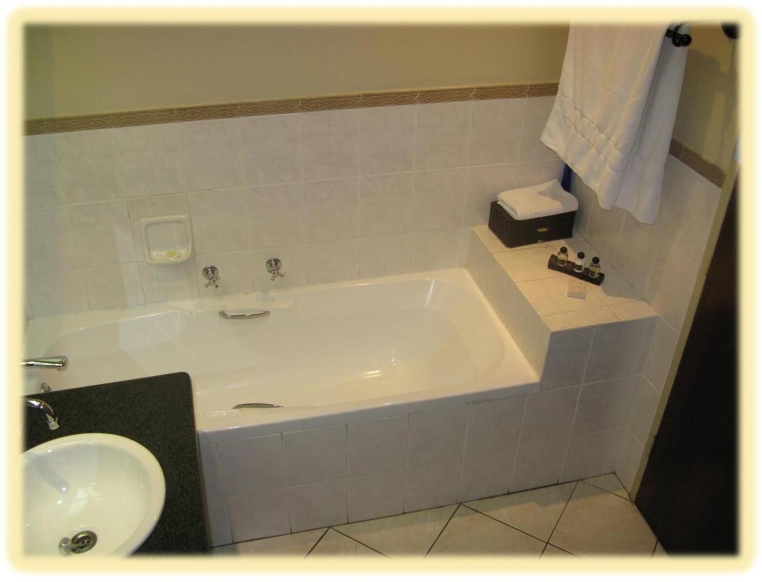 Un baño con bañera, lavamanos y un perchero para toallas.