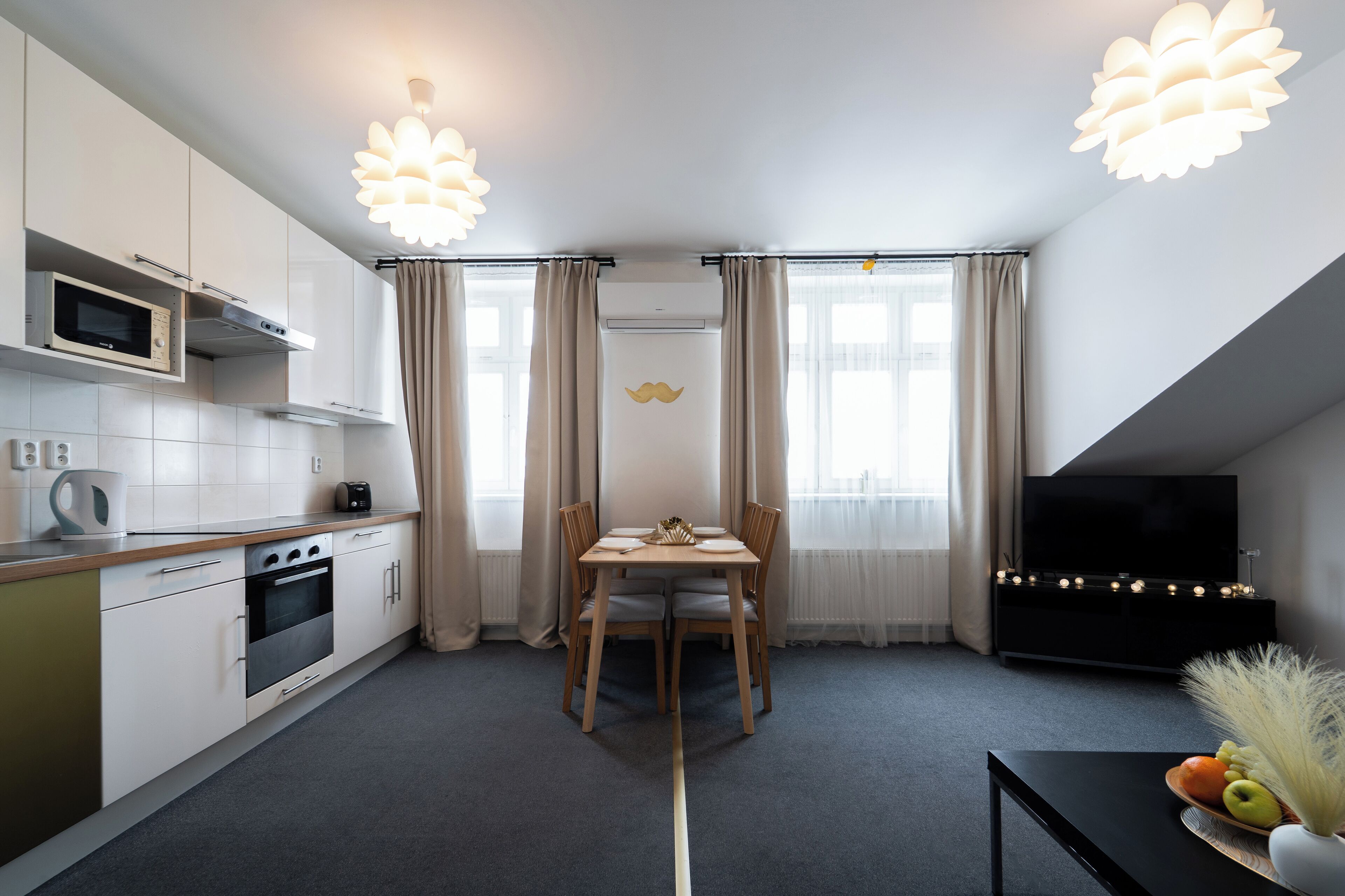 A modern kitchen with a dining area, a flat-screen TV, and a decorative vase on a table.
