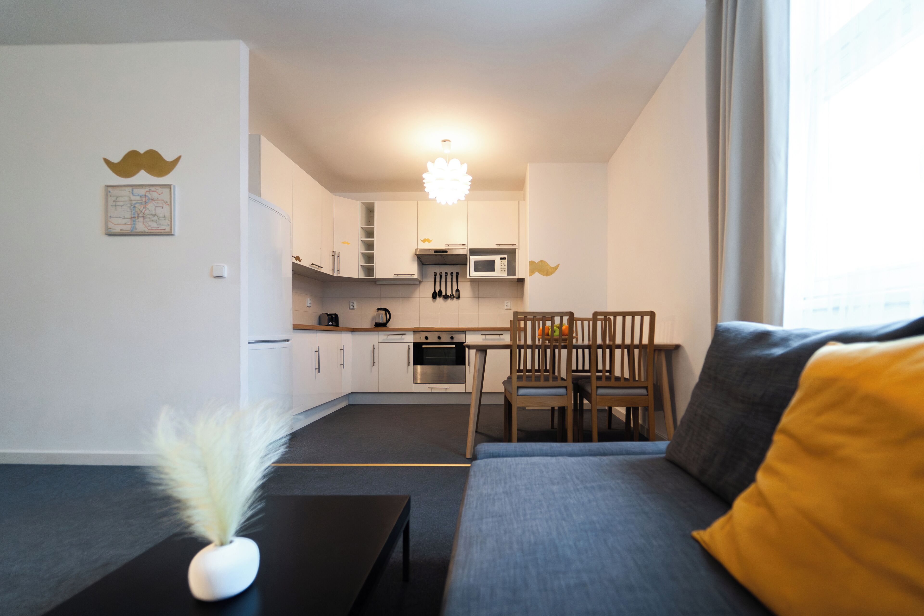 Een modern appartement met een kitchenette, een eethoek en een woonruimte met een bank en een kleine tafel.