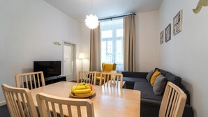 Una sala de estar moderna con una mesa de comedor, sillas, un sofá y una televisión.