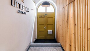 Un pasillo con un cartel que indica 'Little Tom Apartments', un revestimiento de listones de madera y una alfombra estampada.