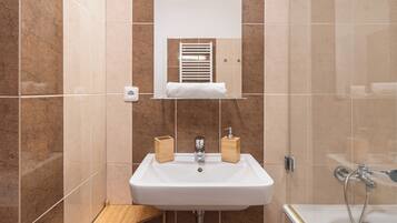 A modern bathroom with a white sink, a mirror, and a shower.