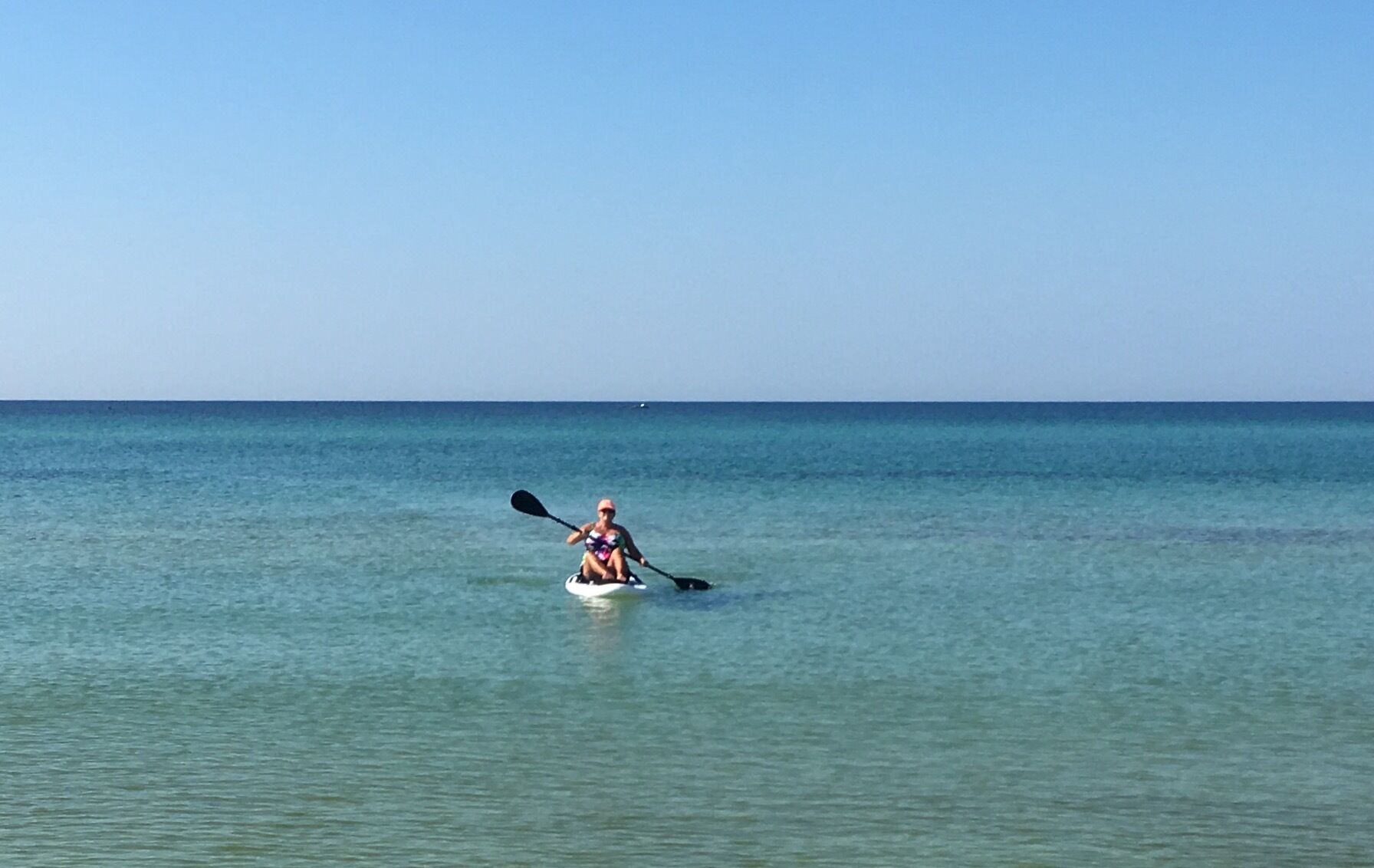 Una persona haciendo kayak en un mar tranquilo.