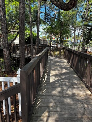 A wooden boardwalk with railings, surrounded by trees and a clear sky. - Park your car and walk everywhere! Including the new beach access! (Santa Rosa)