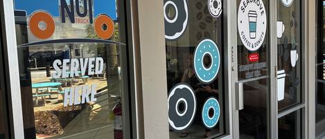 A storefront with a neon 'OPEN' sign, a 'CHARLIE'S DONUT' sign, and a 'SEAGRAVE COFFEE & DONUTS' sign.