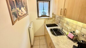 A compact kitchen with a window, a radiator, and a sink with a towel rack. - Apartment Alte Fronfeste II 40sqm (Berchtesgaden)