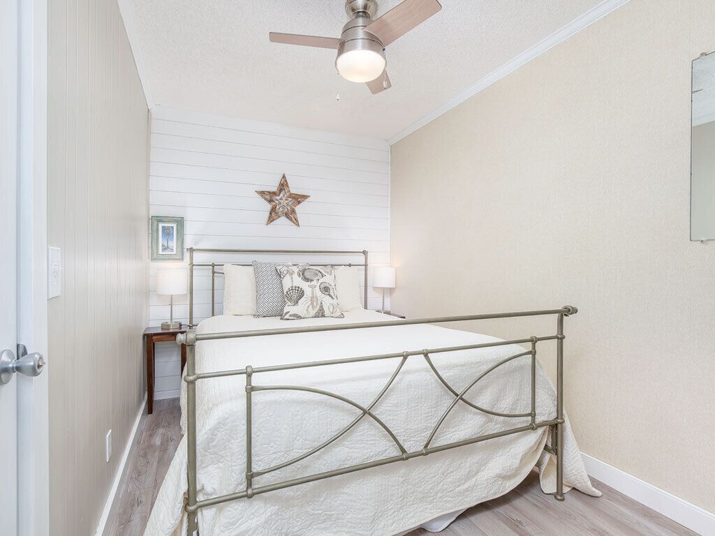 A bedroom with a bed, a ceiling fan, a star decoration, and a bedside table with a lamp.