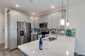 A modern kitchen with stainless steel appliances, a white countertop, and a backsplash with black and white tiles. - Resort Condo in Desirable Chandler.  Tons of Amenities.  Walk to Everything! 30 Night Min! (Chandler)