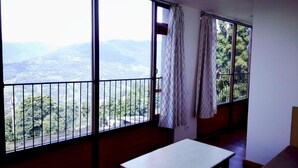 A room with large windows offering a view of a mountainous landscape. - Hotel Ninamma (Gangtok)