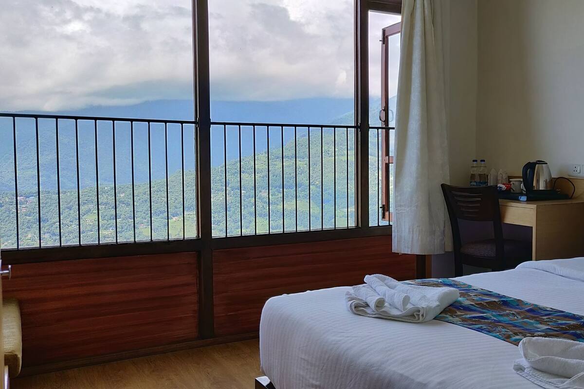 A hotel room with a bed, a desk, and a view of the mountains.