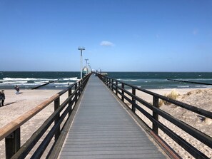 Een houten steiger die zich uitstrekt over de oceaan, met een heldere lucht erboven.