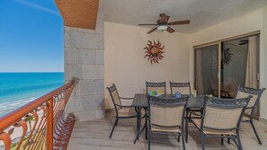 Enjoy the ocean view from this balcony with a table, chairs, and ceiling fan.