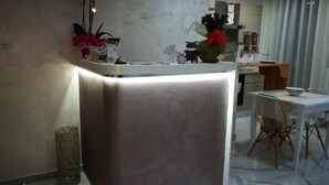 Una cocina moderna con encimera de mármol, un comedor con mesa y sillas blancas, y plantas decorativas.
