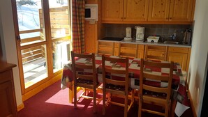 A cozy kitchen with wooden cabinets, a dining table with chairs, and a window with a view of the outdoors.