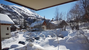 A snow-covered village with traditional houses, a church, and parked cars.
