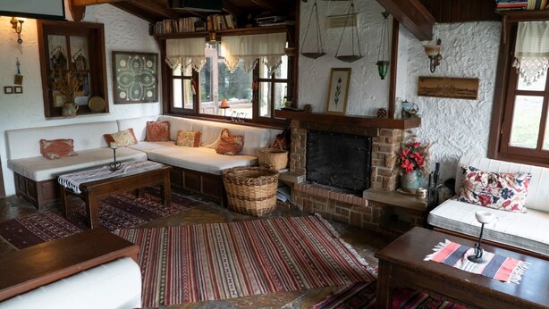 Uma sala de estar acolhedora com lareira, um conjunto de sofás e revestimento de pedra ao redor da lareira.