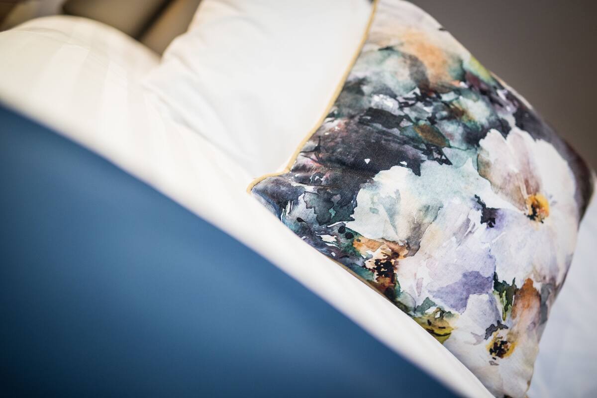 A close-up of a bed with a floral-patterned pillow and a white pillow.