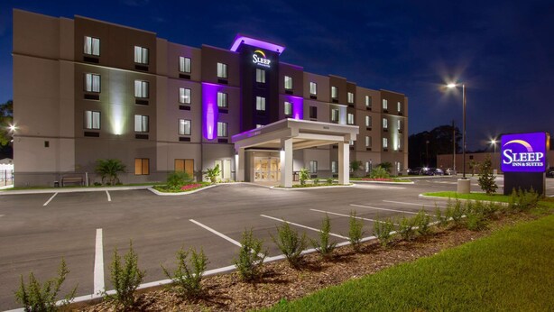 Ein Sleep Inn & Suites Hotel mit modernem Design, das einen zentralen Eingang und mehrere Etagen aufweist.