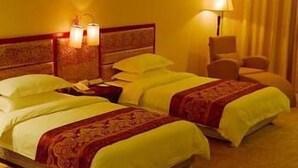 A hotel room with two beds, a nightstand, a lamp, and a chair. - King We Holiday Hotel (Quanzhou)