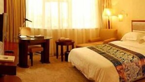 A hotel room with a bed, a desk, a chair, and a lamp. - King We Holiday Hotel (Quanzhou)