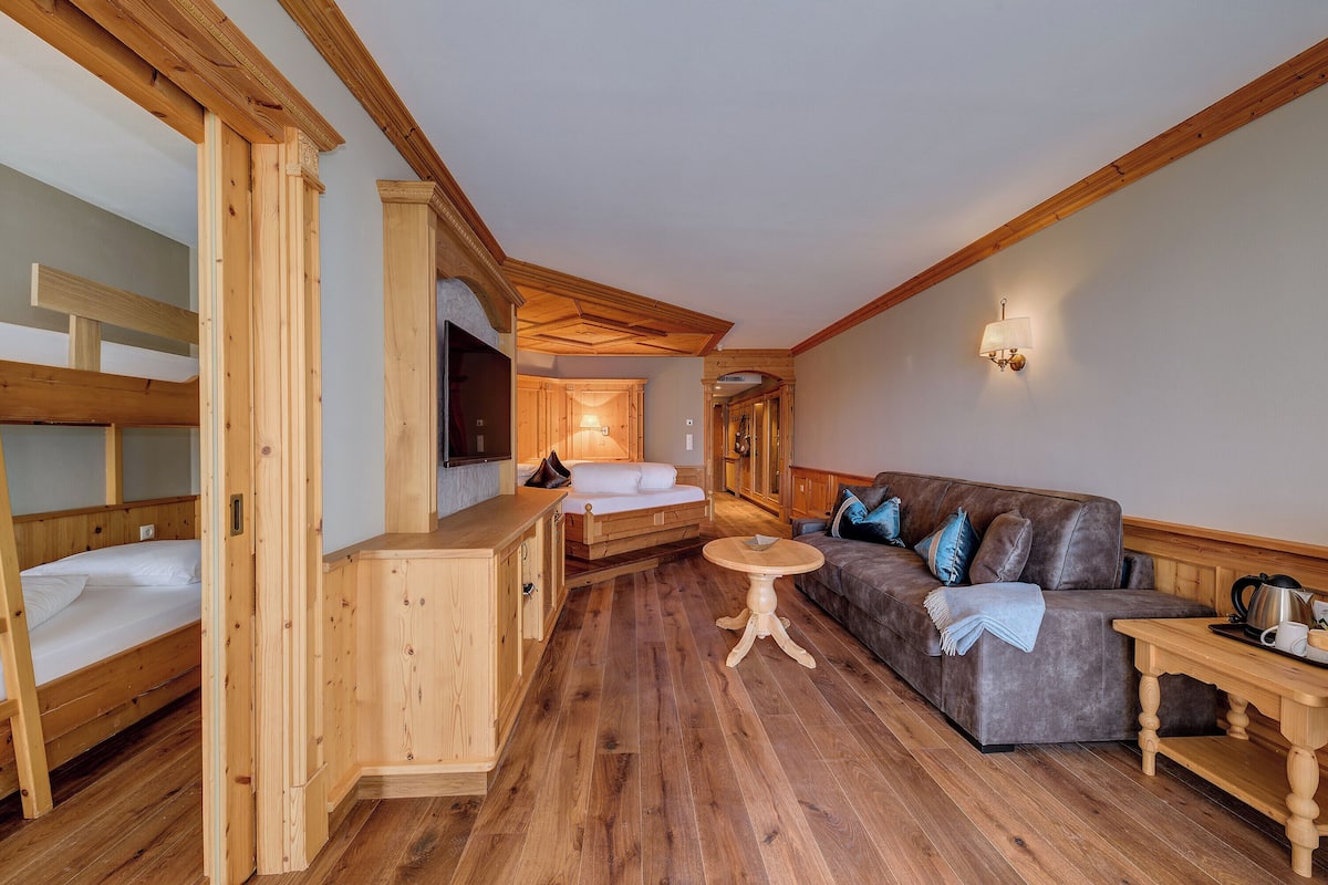 Un intérieur en bois avec un lit superposé, un canapé et une table ronde.