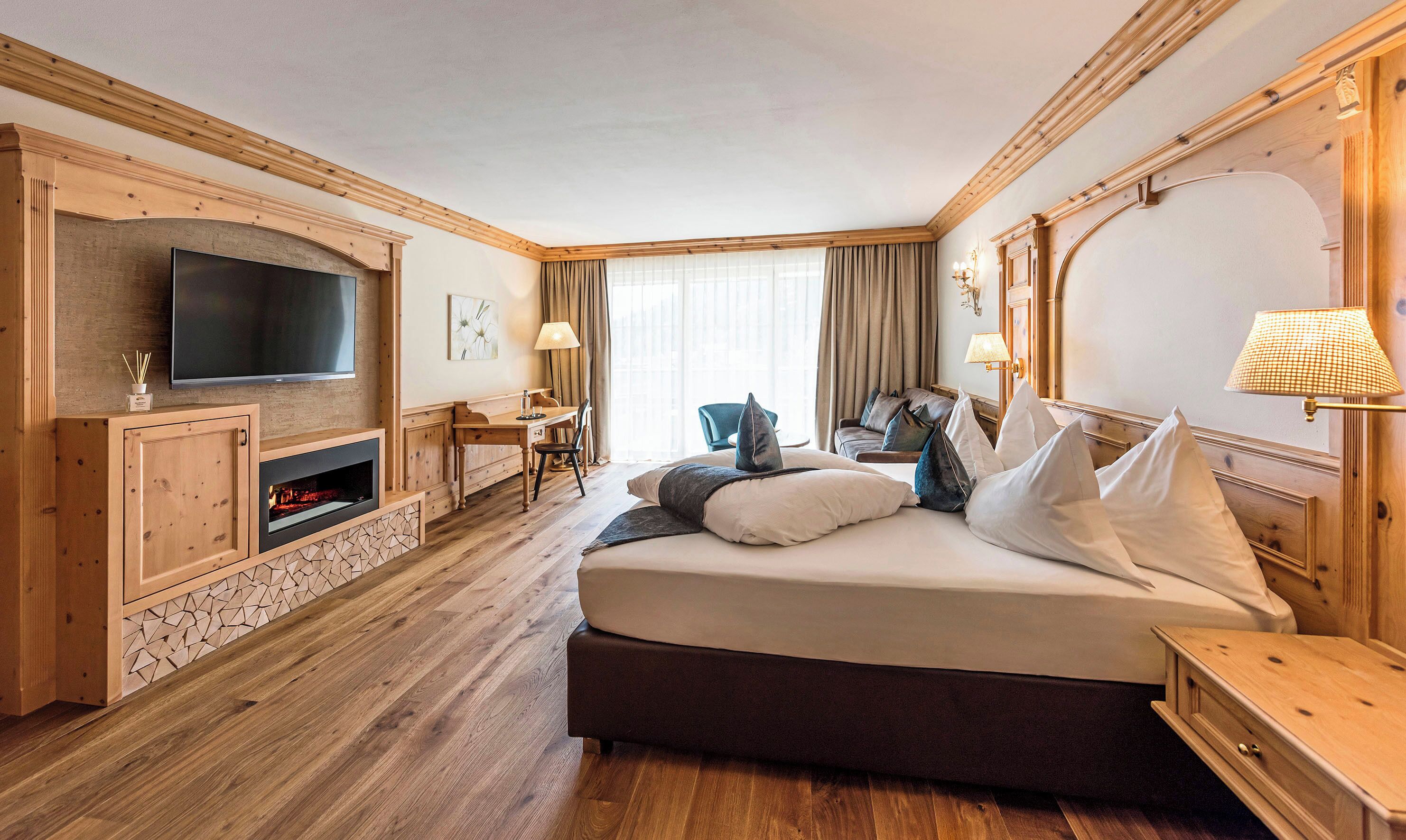 Habitación de hotel con una cama grande, televisión, chimenea, escritorio y una silla.