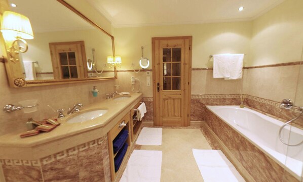 A bathroom with two sinks, a bathtub, and a door. - Quellenhof Luxury Resort Passeier (San Martino in Passiria)