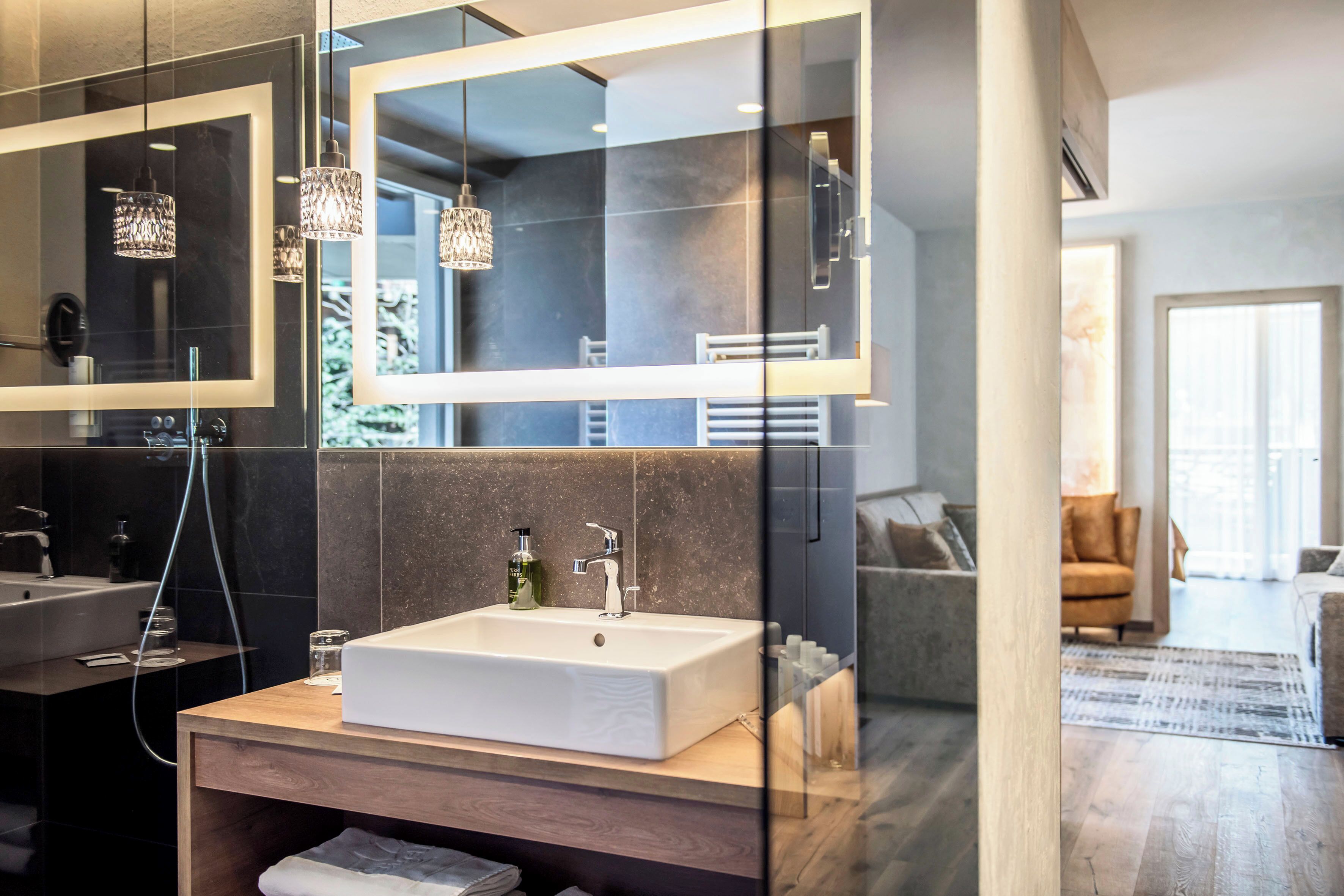 A modern bathroom with a large mirror, a white sink, and a wooden vanity.