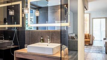 A modern bathroom with a large mirror, a white sink, and a wooden vanity.