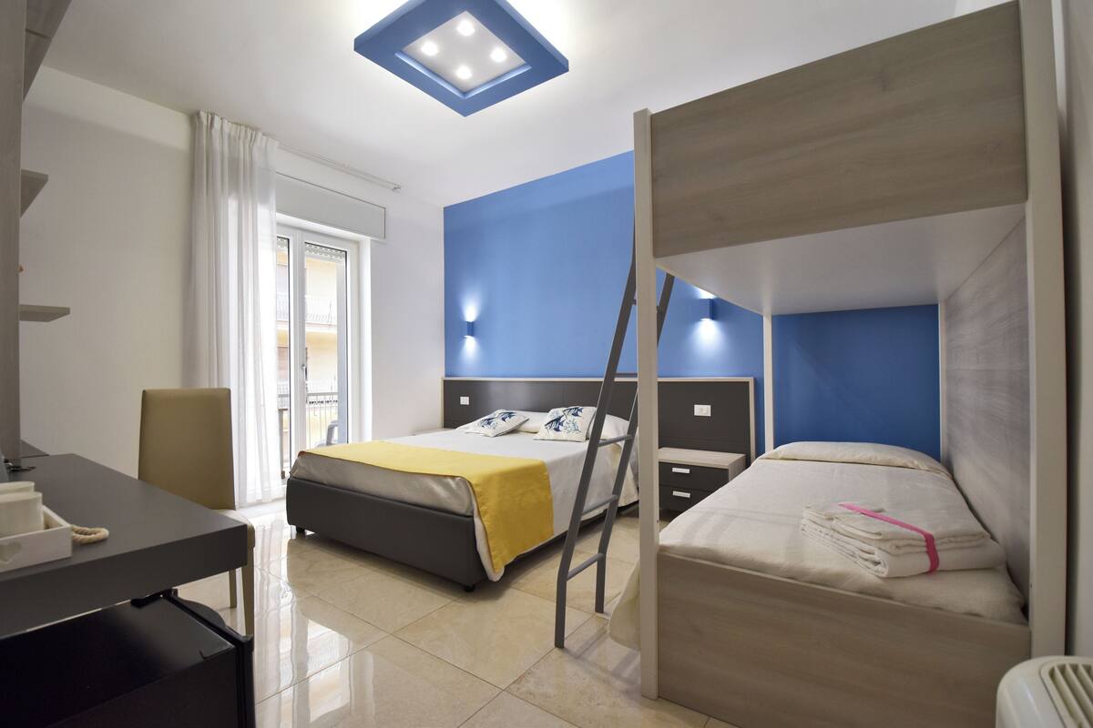Una habitación de hotel con una cama, un escritorio, una silla y una ventana.