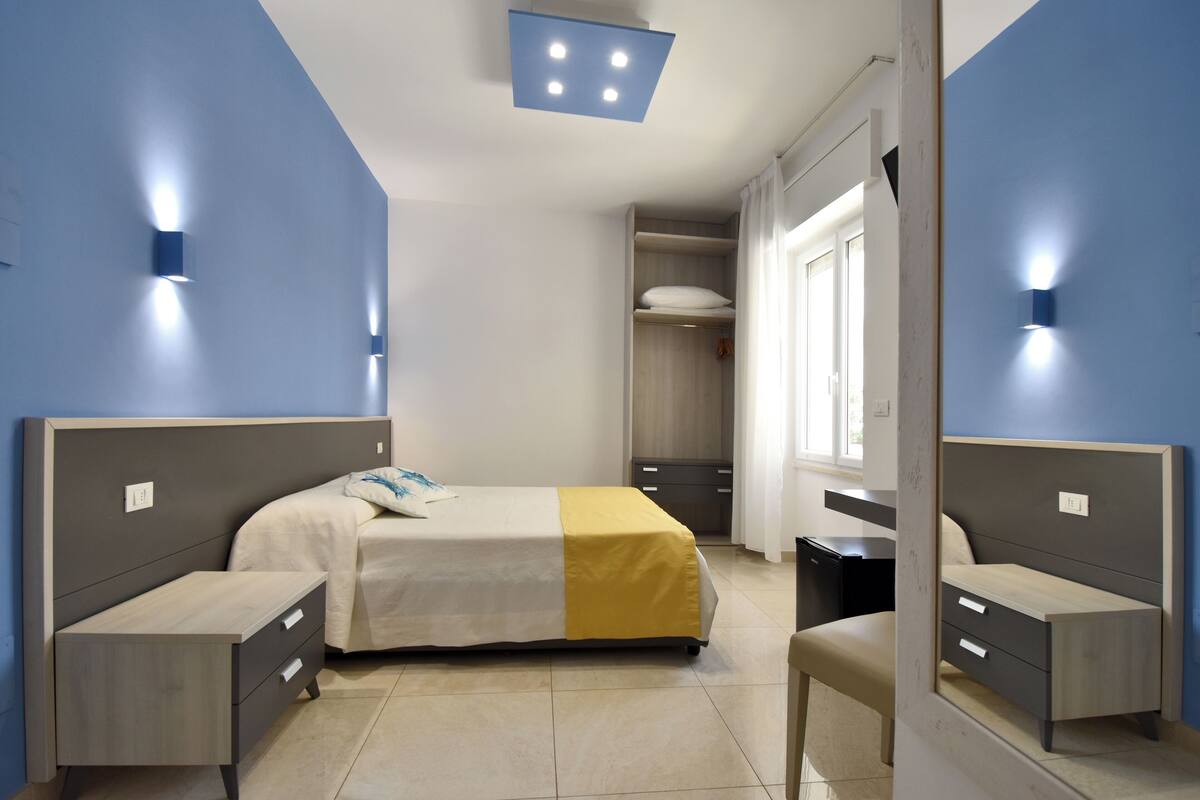 Un dormitorio moderno con cama, mesitas de noche y armario.