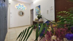 Un pasillo con un espejo, un aplique en la pared y una puerta.