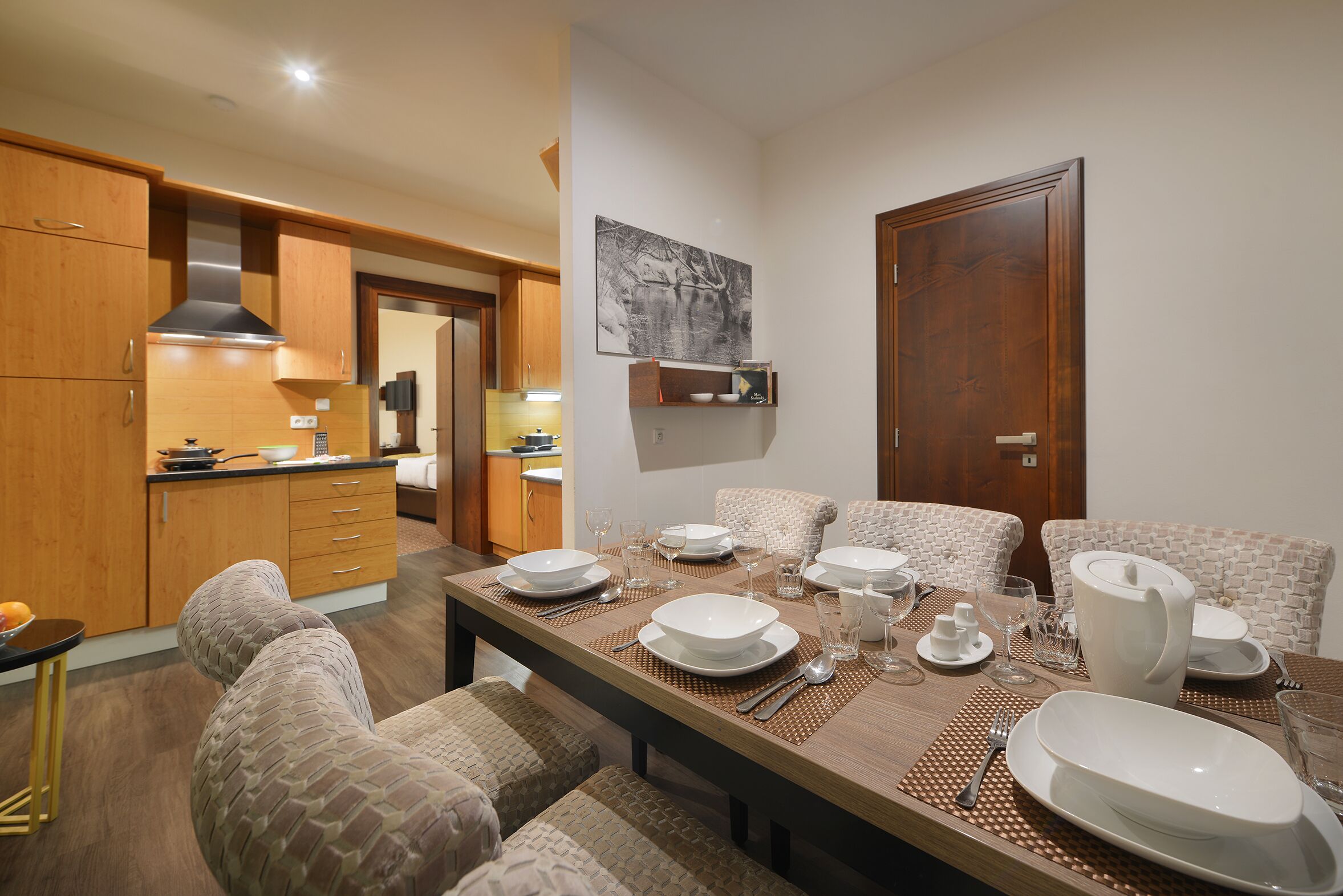 A dining area with a wooden table set for four, surrounded by cushioned chairs.