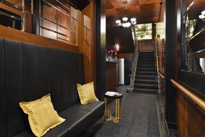 A modern interior with a black leather bench, a small round table, and a staircase leading to an upper level. - Vysocina Design Apartments (Hlinsko)