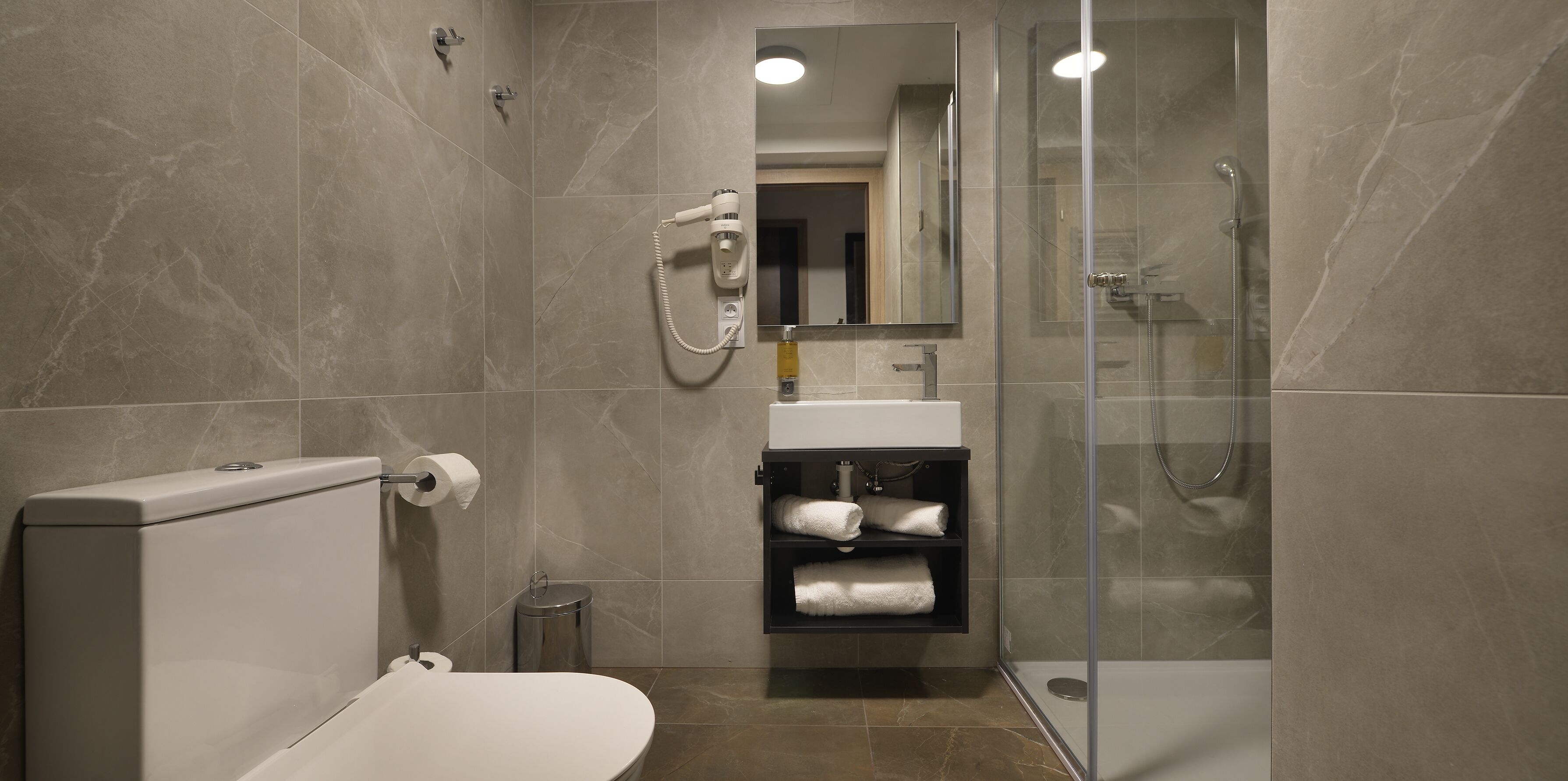 A modern bathroom with a toilet, sink, and shower.