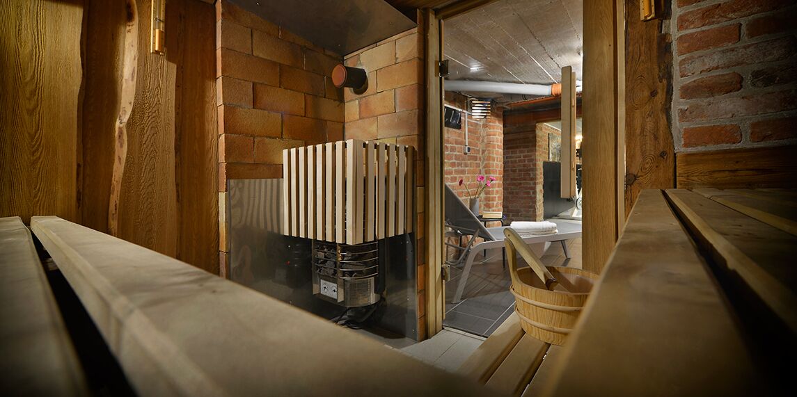 A narrow, rustic room with exposed brick walls, a radiator, and a wooden bench.